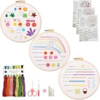 The Embroidery Stitch Practice Kit 4 includes sample hoops with various stitches, coloured threads, scissors, needles, a threader, and instructional booklets—all arranged neatly on a white background.