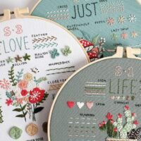 The Embroidery Stitch Practice Kit 2 includes three hoops with floral designs, labelled LOVE, LIFE, and JUST SEE. Each hoop displays colourful flowers, leaves, and a variety of stitching techniques on fabric.