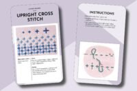 The Essential Embroidery Stitches Card Deck by Betty Barnden includes two cards for upright cross stitch: one with a photo of blue stitches and instructions, and the other featuring a step-by-step diagram with a stitched needle illustration.