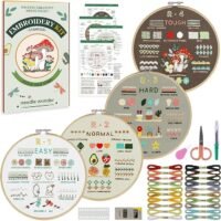 The Embroidery Stitch Practice Kit 7 includes instruction sheets, four embroidery hoops with different stitch patterns, colourful threads, needles, threaders, scissors, and additional sewing tools all neatly arranged.