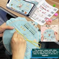 A person uses the Embroidery Stitch Practice Kit 8 with light blue fabric in a hoop, following a printed and phone-displayed guide featuring video tutorials, illustrations, and QR codes for beginners.