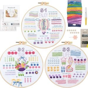 The Embroidery Stitch Practice Kit 13 includes three hoops with colourful stitched patterns, assorted embroidery threads, needles, needle threader, buttons, ribbon, and an instruction booklet arranged neatly around the hoops.