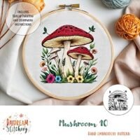 Hand embroidery hoop featuring a vibrant design of three red-capped mushrooms with flowers and greenery, including the Mushroom 10: Hand embroidery pattern and step-by-step instructions.