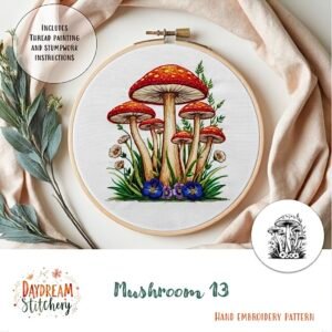 A hand embroidery hoop shows colourful mushrooms, green grass, and blue flowers. Decorative leaves and a metal threader are nearby. Text: Mushroom 13: Hand embroidery pattern with instructions. Logo: Daydream Stitchery.