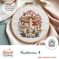 The Mushroom 4: PDF hand embroidery pattern features three red-capped mushrooms with white stems, surrounded by green leaves and small flowers, and comes with thread painting and stumpwork instructions.