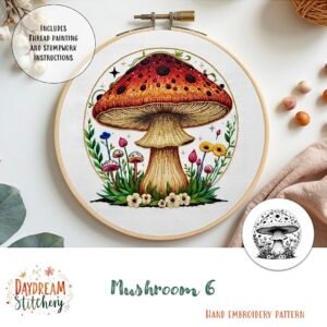 A hand embroidery hoop displays a detailed red and brown mushroom with grass, flowers, and colourful accents. The text reads "Mushroom 6a: Hand embroidery pattern" by Daydream Stitchery.