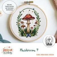 A round hoop displays the colourful Mushroom 7a hand embroidery pattern with mushrooms, ferns, and flowers. Speech bubbles highlight included thread painting and stumpwork instructions. Pattern by Daydream Stitchery.